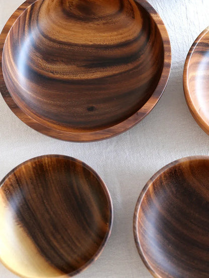 Brown handmade wooden serving bowl with natural wood grain on a table.