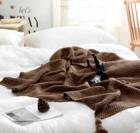 Nordic style fringed knit acrylic blanket in beige colour on a sofa