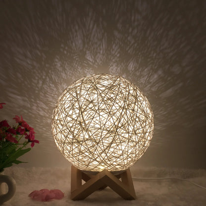 Spherical hand-knitted rattan table lamp with remote control on a wooden desk