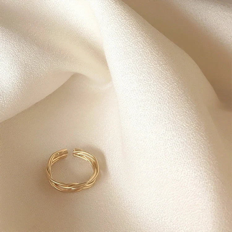 Adjustable twist metal ring in a gold tone, featuring a modern geometric design with a vintage-inspired flair.