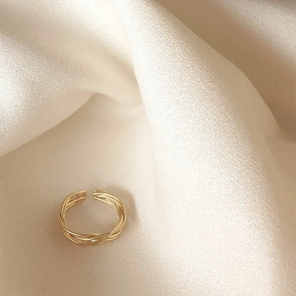 Adjustable twist metal ring in a gold tone, featuring a modern geometric design with a vintage-inspired flair.