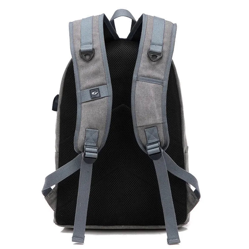 Coffee-coloured canvas backpack with USB charging port on side strap and front zipper pocket.