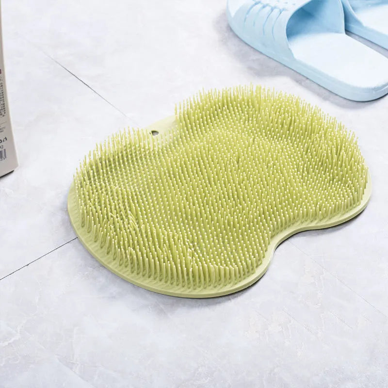 Orange non-slip massage bath brush with silicone bristles and suction cup base on shower floor