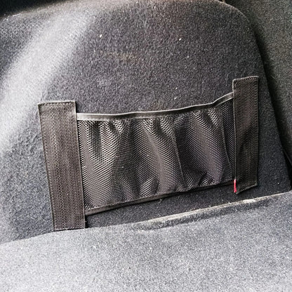 A stretchy polyester car boot storage net in a vehicle trunk, holding loose items securely.