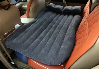 Black inflatable car bed with flocked surface and two pillows, shown folded into a chair inside a vehicle.