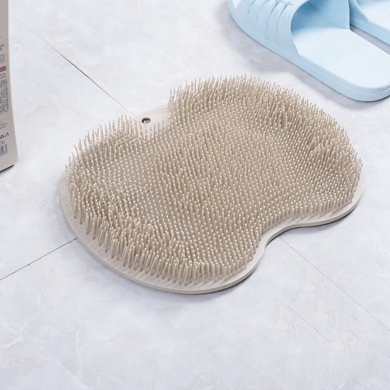 Orange non-slip massage bath brush with silicone bristles and suction cup base on shower floor