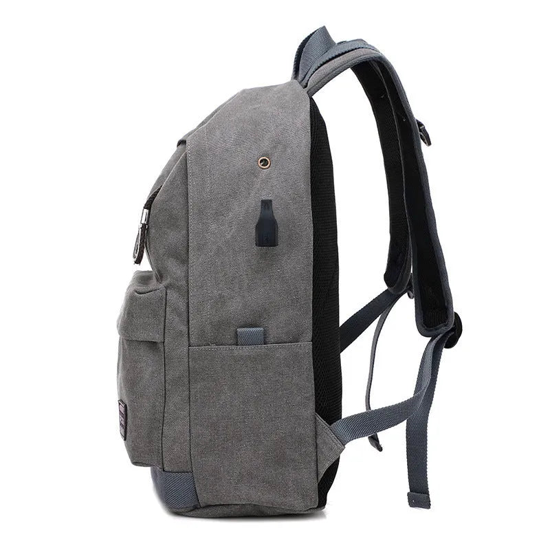 Coffee-coloured canvas backpack with USB charging port on side strap and front zipper pocket.