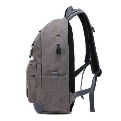 Coffee-coloured canvas backpack with USB charging port on side strap and front zipper pocket.