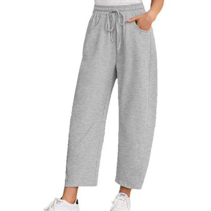 Loose fit cropped sweatpants in apricot colour with drawstring waist and side pockets on a neutral background.