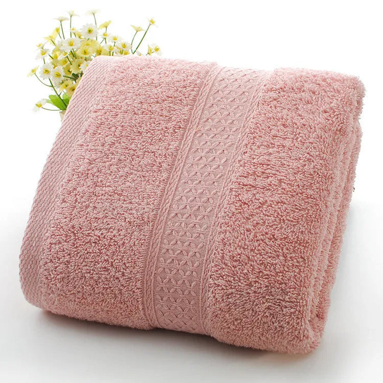 A stack of thickened cotton bath and beach towels in various colours including apple green, dark blue, and light pink.