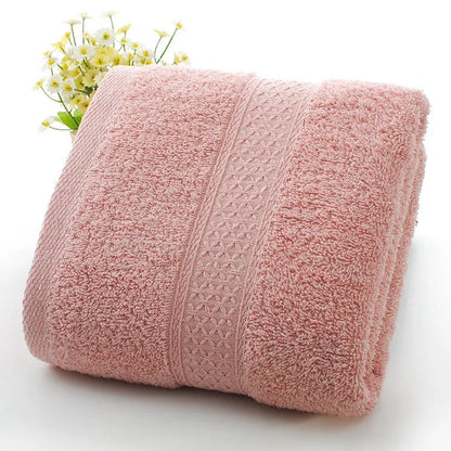 A stack of thickened cotton bath and beach towels in various colours including apple green, dark blue, and light pink.