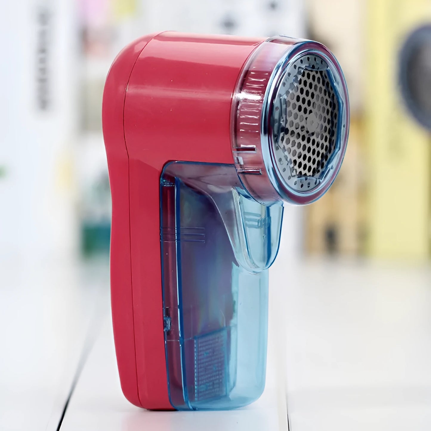 White portable electric lint remover on a blue sweater, showing compact size and shaver head.