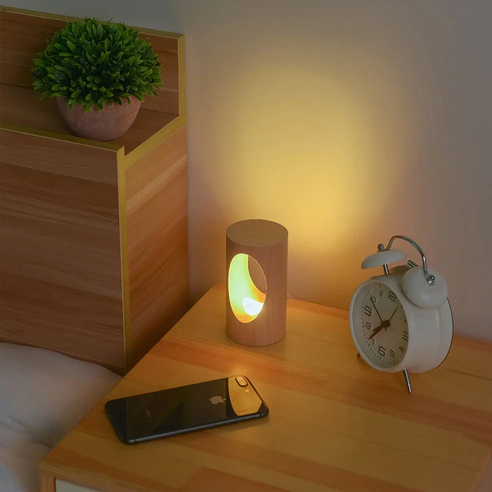 Solid wood LED reading lamp with adjustable arm and glass holder on wooden surface