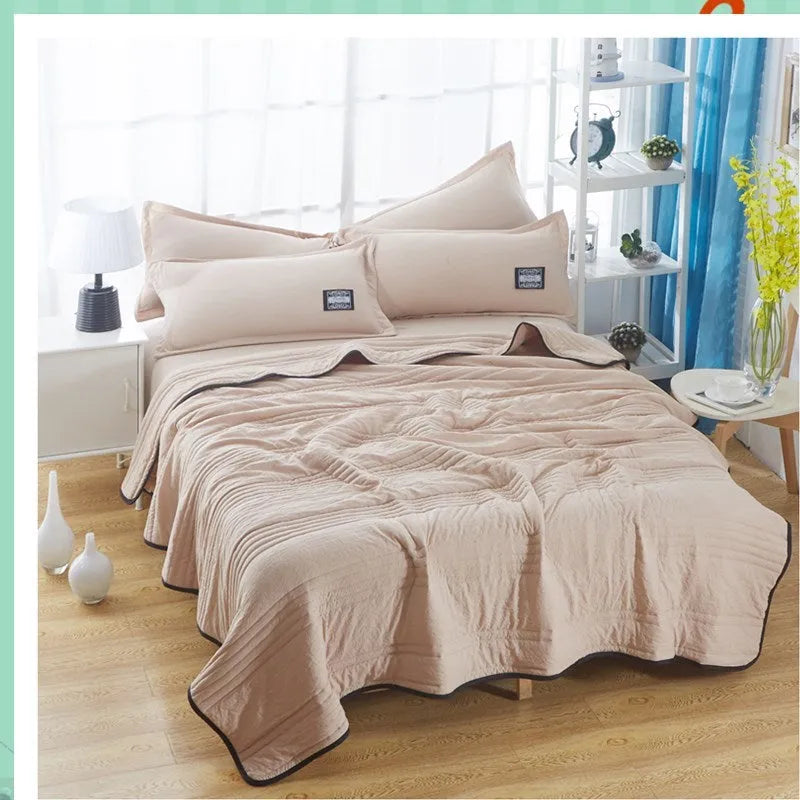 Lightweight plain coloured polyester summer quilt on a bed