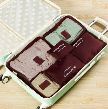 Set of six coloured nylon packing cubes and flat pouches for travel organisation.