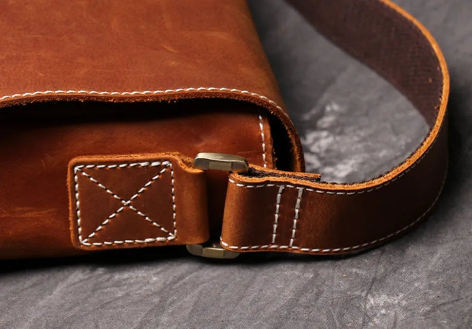 Vintage brown leather men's messenger bag with a cover flap, showing the internal document and phone pockets.