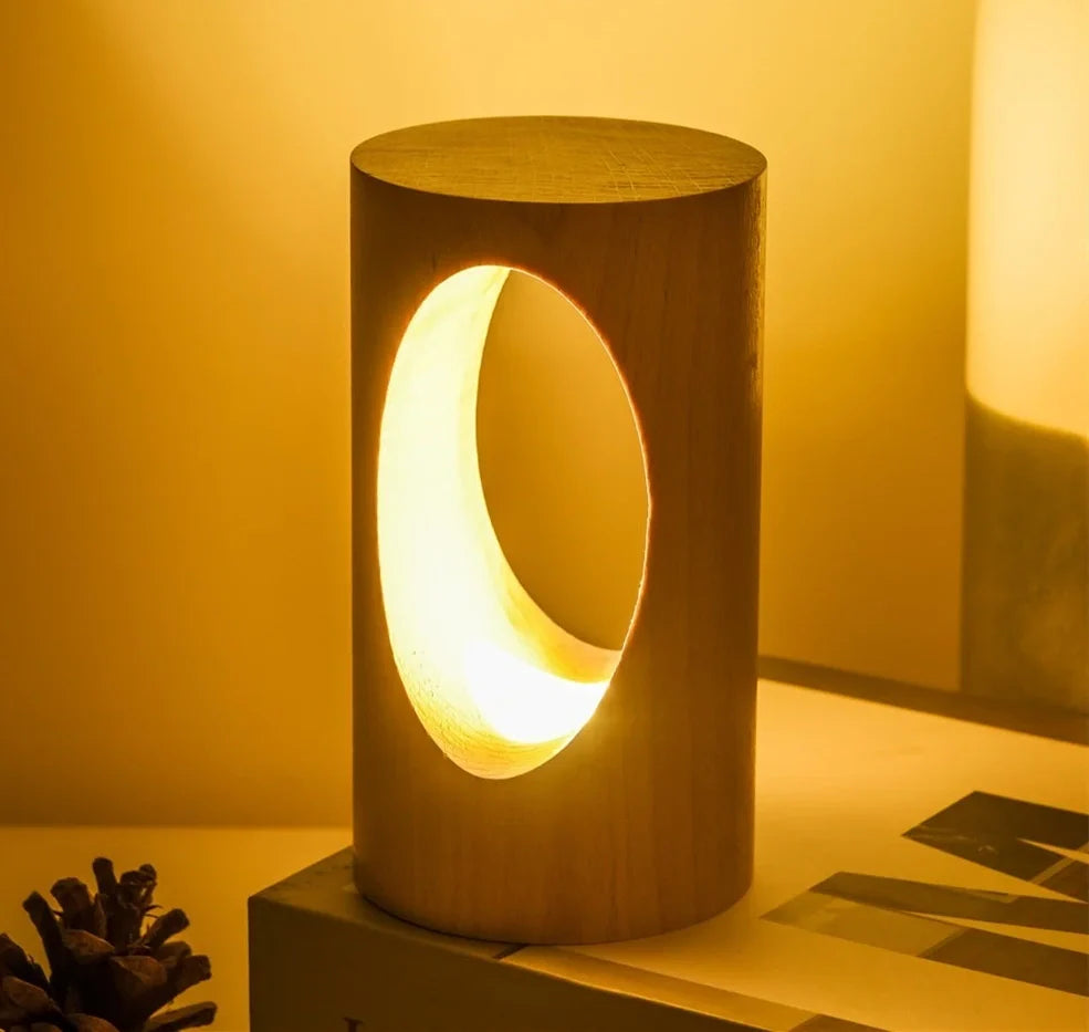 Solid wood LED reading lamp with adjustable arm and glass holder on wooden surface