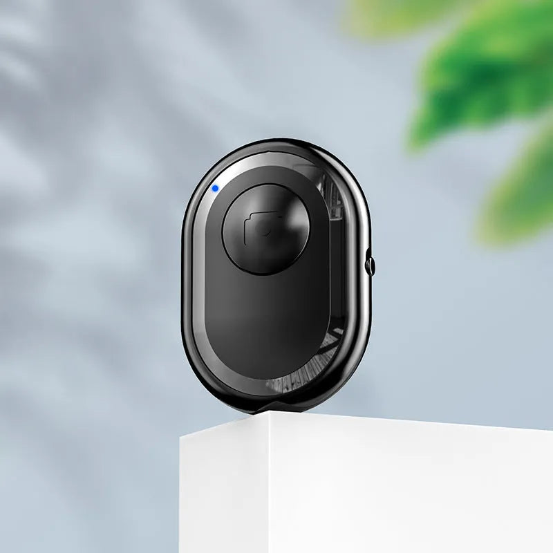 Small black wireless Bluetooth remote control for smartphone camera with self-timer function.
