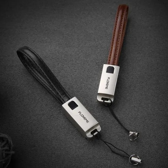 Short black leather iPhone charging cable with metal connector next to a power bank
