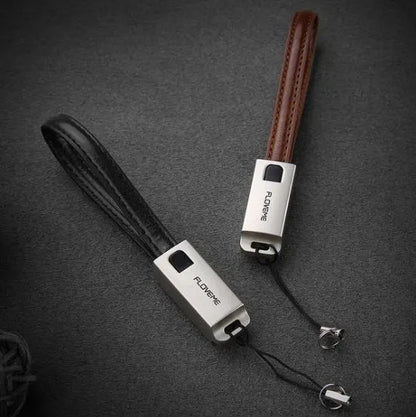 Short black leather iPhone charging cable with metal connector next to a power bank
