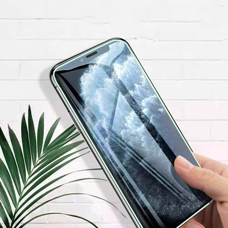 Luminous tempered glass screen protector glowing in dark next to iPhone