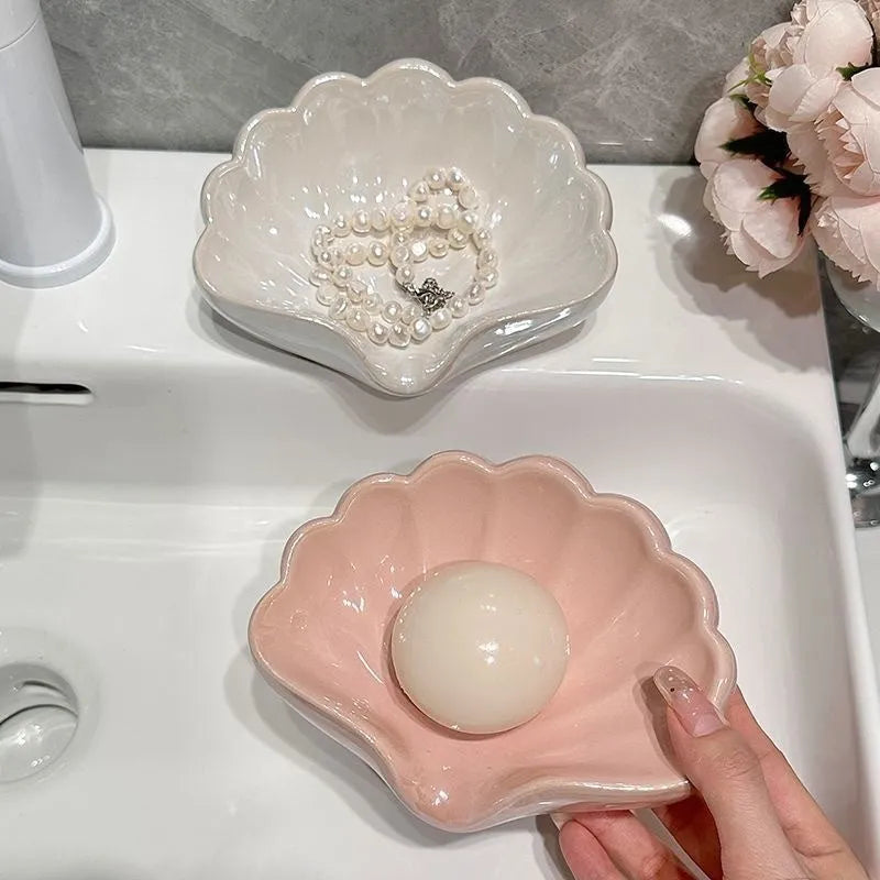 Plastic shell soap dish in pearl white, dimensions 12x9x5.5cm, on a bathroom counter