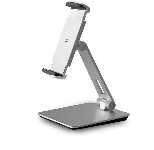 Silver foldable aluminium phone and tablet holder on a wooden desk, showing 360-degree rotation and silicone pads.