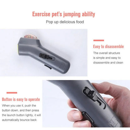 Grey plastic pet snack catapult launcher toy with ergonomic handle, shown with treats.