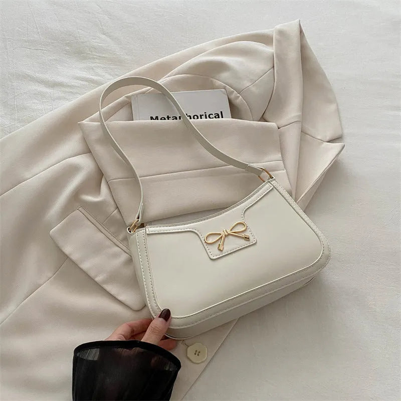 Western style shoulder bag with bow detail in rose pink colour, showing horizontal square shape and single strap.