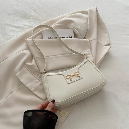 Western style shoulder bag with bow detail in rose pink colour, showing horizontal square shape and single strap.
