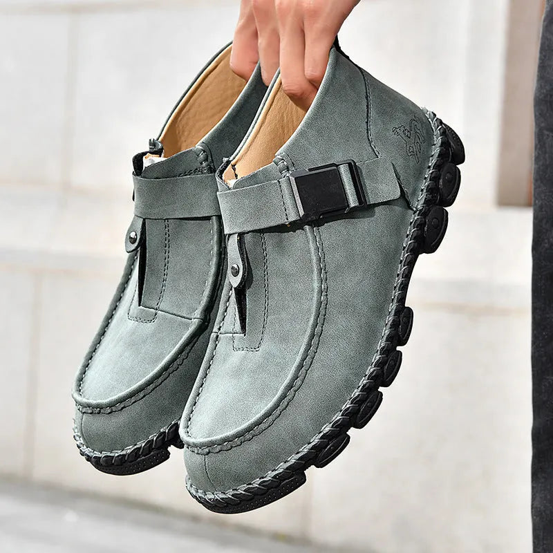 Casual flat bottom slip on shoes in brown with visible handmade sole stitching on a wooden floor.