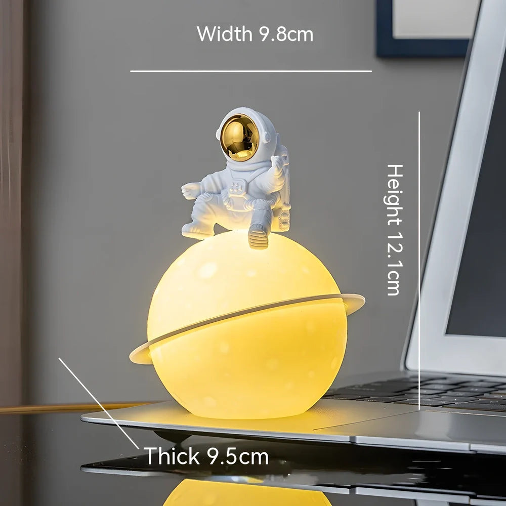 Astronaut planet night lamp in golden finish, 12 cm tall PVC ABS figure with glowing 3 cm orb on 5 cm base