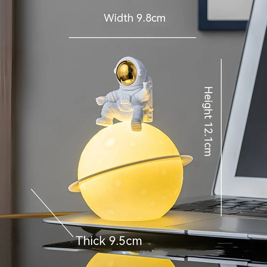 Astronaut planet night lamp in golden finish, 12 cm tall PVC ABS figure with glowing 3 cm orb on 5 cm base