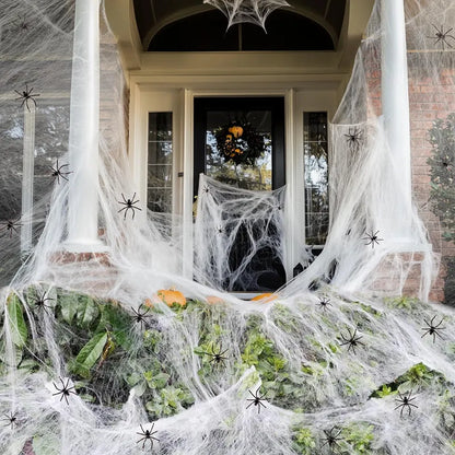 White cotton spider web Halloween decoration with multiple spiders draped over furniture for spooky atmospheric display
