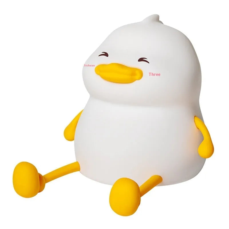 Chubby Night Light with soft glow on bedside table, holding a mobile phone in its silicone cradle.