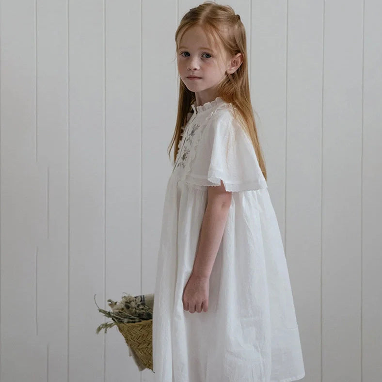 White cotton girls dress with embroidered skirt detail, short sleeves, and Western style silhouette