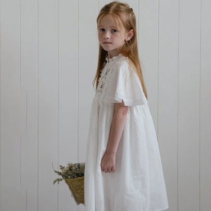 White cotton girls dress with embroidered skirt detail, short sleeves, and Western style silhouette