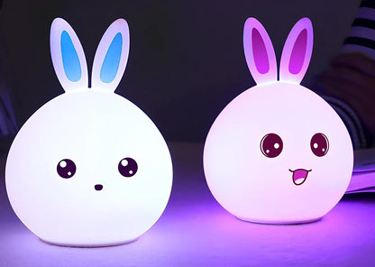 White silicone rabbit night light with USB charging cable showing touch sensor area and colourful LED illumination