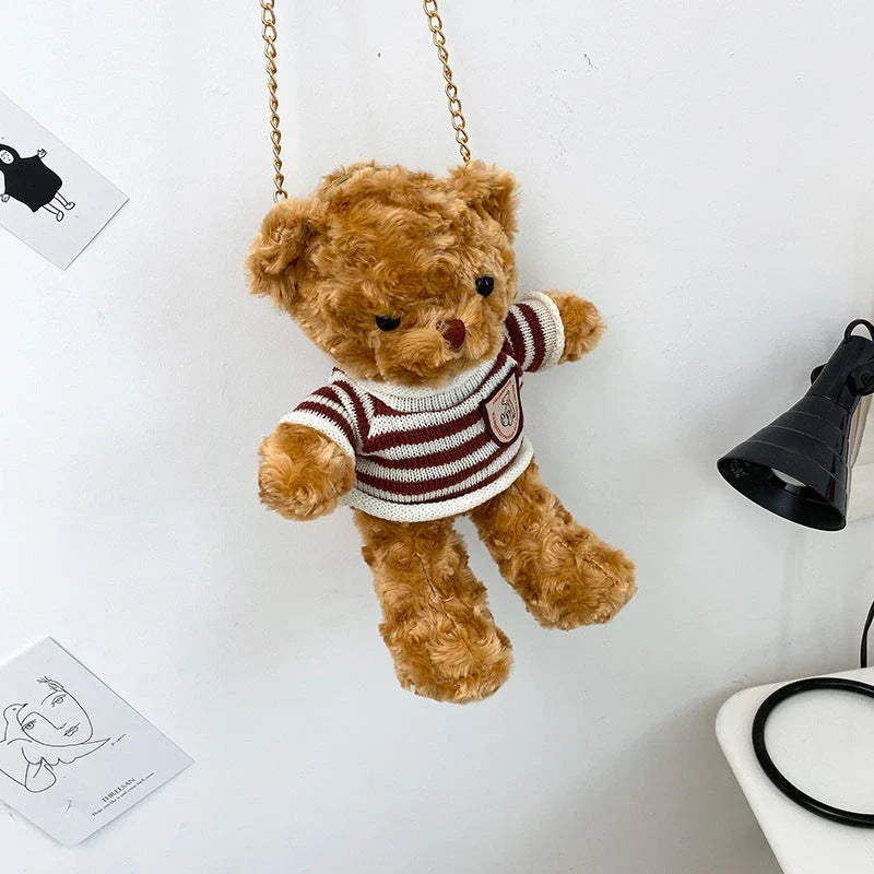 A plush teddy bear crossbody messenger bag with an adjustable shoulder strap and a zippered interior pocket for convenient storage.