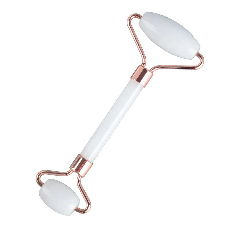 White jade facial roller with double heads and matching scraping board on dark surface