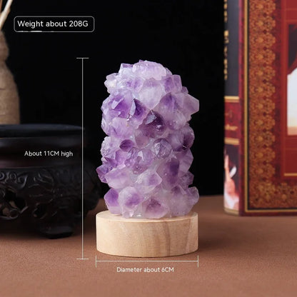 Miniature amethyst crystal tooth flower night light glowing with warm light on a wooden surface.