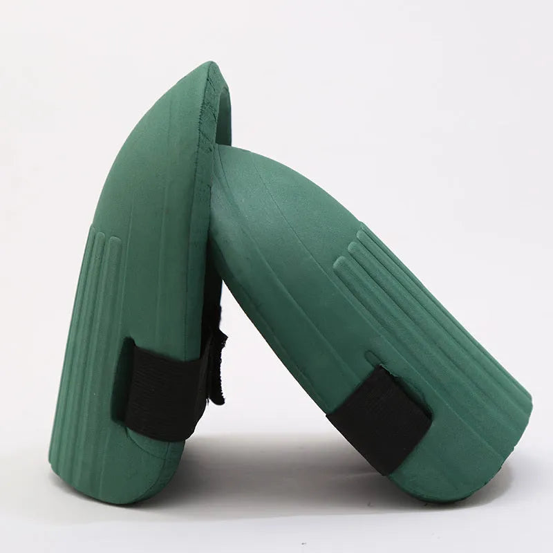A pair of rectangular EVA foam knee pads in army green colour, placed on a garden soil background.