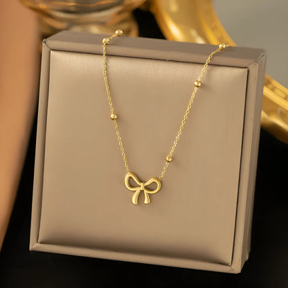 Gold titanium steel necklace with bow pendant on an adjustable cross chain, length 41cm to 50cm.