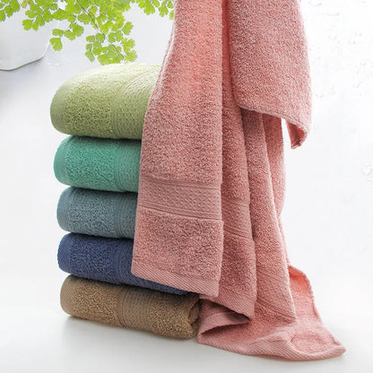 A stack of thickened cotton bath and beach towels in various colours including apple green, dark blue, and light pink.