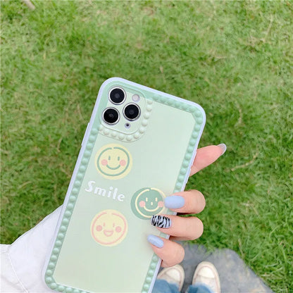Green TPU iPhone case with geometric smiley face and polka dot frame design on a smartphone
