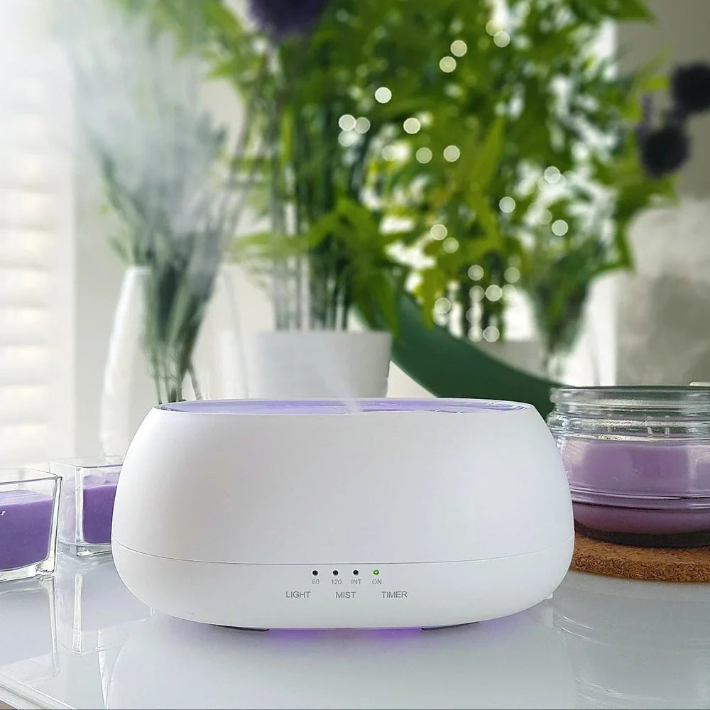 White HOMEFISH aroma diffuser with colour-changing LED light displaying blue hue, remote control beside unit