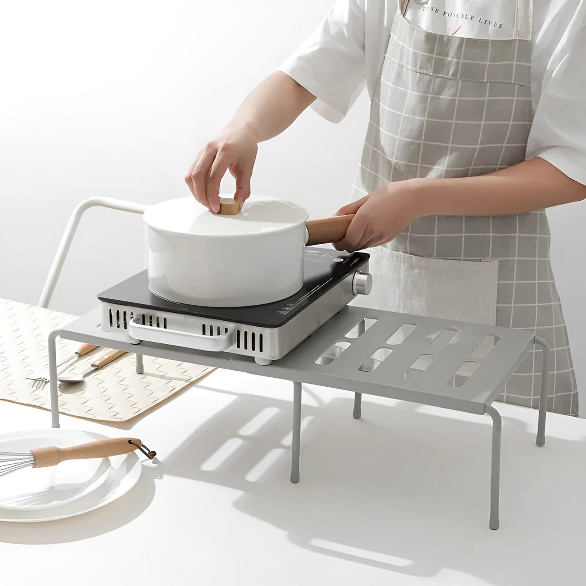 White telescopic kitchen storage rack at adjustable height on a countertop