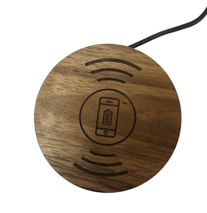 Round wireless charging unit for recessed installation in desks and tables, shown next to a smartphone.