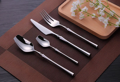 Four-piece stainless steel cutlery set showing main knife, fork, spoon, and teaspoon with mirror finish