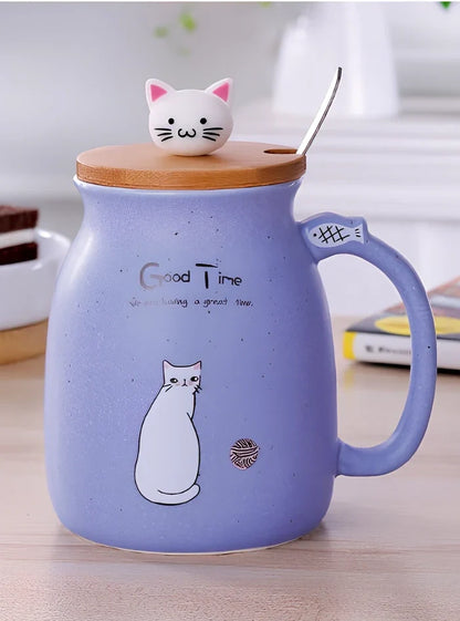 Pink ceramic mug with cartoon cat design, wooden lid, and stainless steel spoon on table